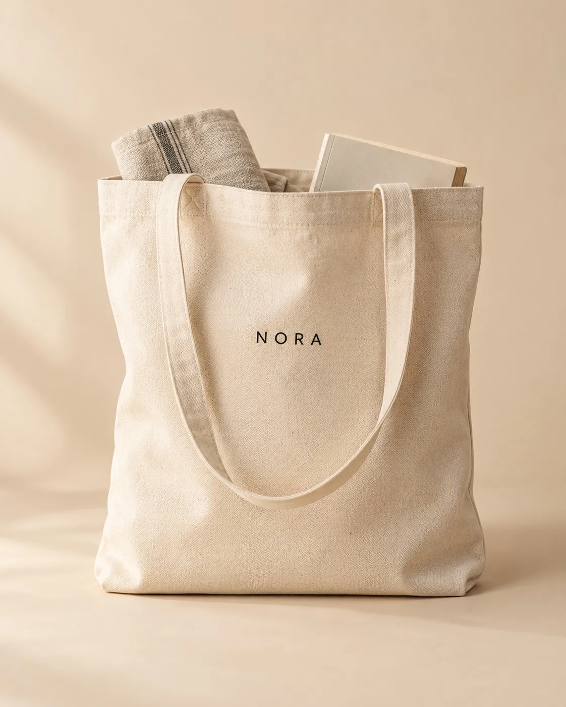 Bolsa tote de algodón natural con un logo ficticio en vinilo negro.