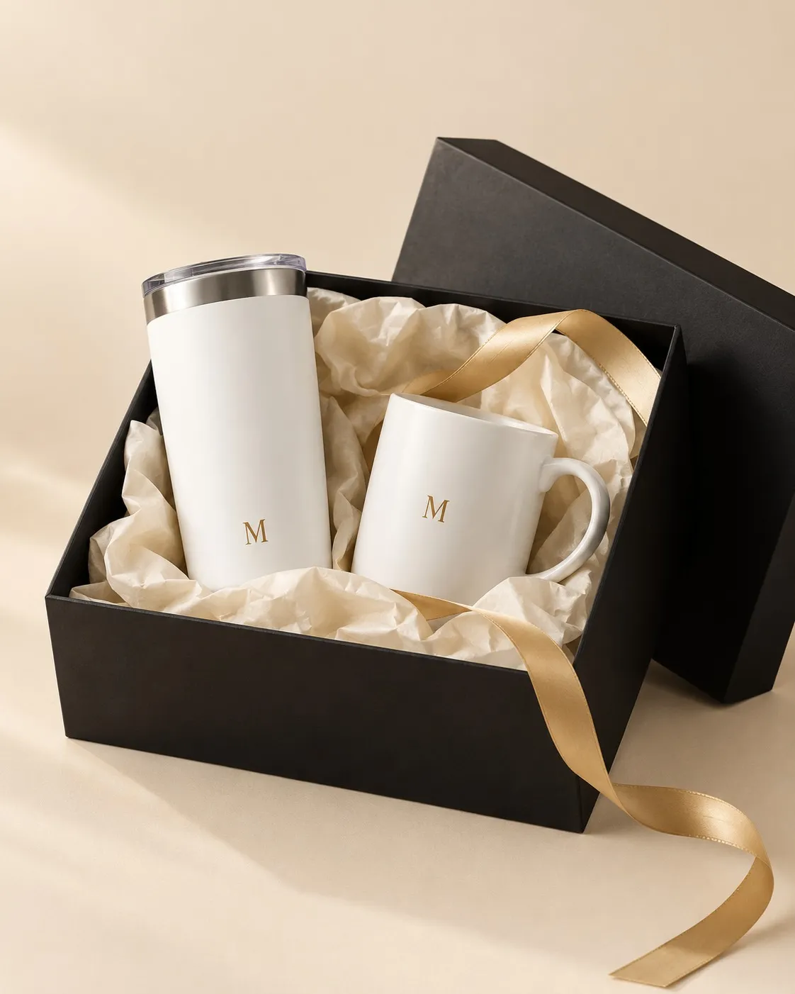 Caja negra de regalo con termo y taza con un monograma discreto, cinta dorada.