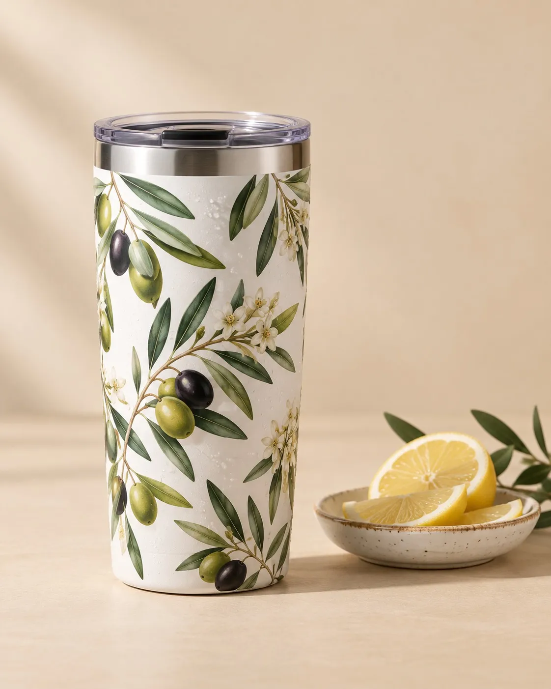 Termo blanco de acero con un estampado botánico a todo color, junto a un plato con limón.